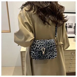 Détail du sac bandoulière léopard avec fermoir goutte doré sur une texture en tissu doux