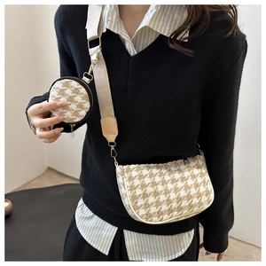 Detail of houndstooth crossbody bag with wide strap and round coin purse attachment