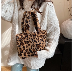 Detail einer Handtasche mit Leopardenmuster aus Kunstpelz, kombiniert mit weißem Strickpullover