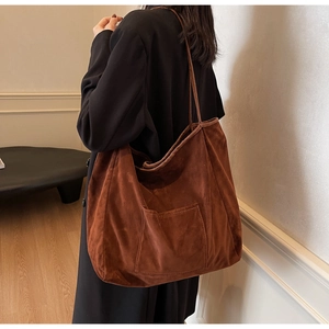 Detail view of large brown suede tote bag worn over shoulder showing spacious capacity