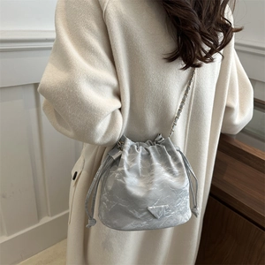 Chic silver bucket bag with marble texture and chain strap, shown on a female model