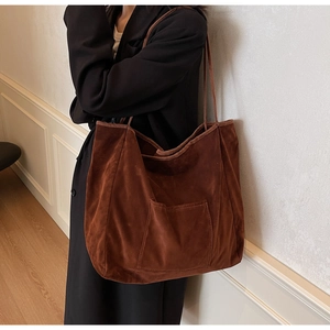 Detail of a large brown suede tote bag worn on shoulder for stylish autumn commuting