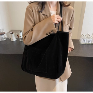 Detailed close-up of a black corduroy tote bag featuring a textured side pocket and soft fabric