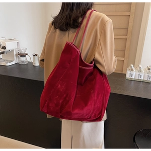 Detail of red oversized velvet tote bag with exterior side pocket and long shoulder straps
