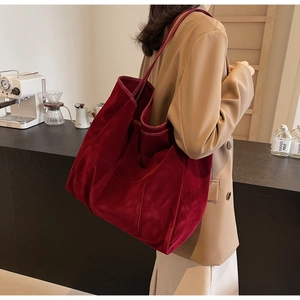 Detail of burgundy velvet tote bag worn on shoulder for stylish commuting look