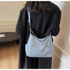 Detailed view of blue denim hobo bag with adjustable strap and silver zipper pockets