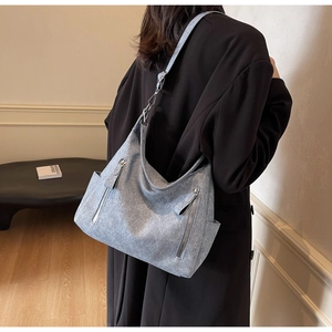 Detail of blue-grey textured hobo bag with front zippers and wide shoulder strap