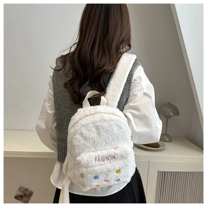 Détail d'un sac à dos en peluche blanche avec broderie rose et pois colorés décoratifs
