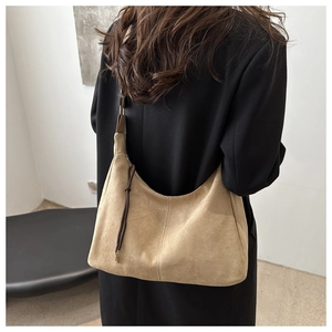 Detail of camel suede hobo bag with contrast stitching and brown leather string detail