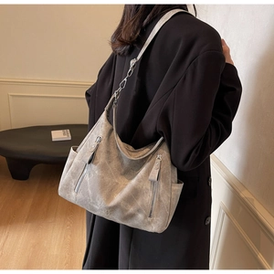 Detail of grey vintage textured shoulder bag with vertical zippers and metallic hardware