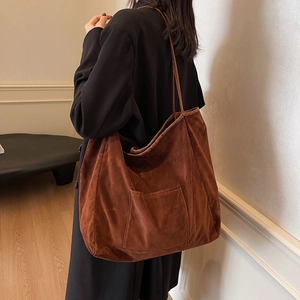 Brown suede tote bag with front pocket shown in a minimalist interior lifestyle setting