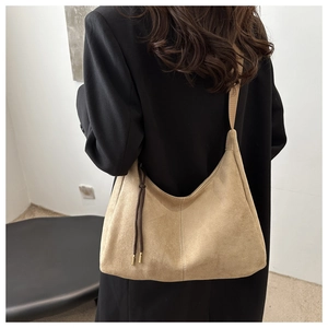 Detail view of large apricot suede tote bag with white stitching on black jacket