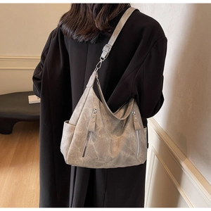 Detailed view of the large grey suede-textured tote bag with dual zippers worn by a model