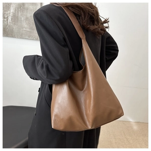 Detailed side view of the brown large capacity PU leather tote bag worn by a model