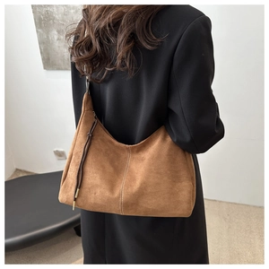 Close-up of brown suede tote bag featuring white contrast stitching and side drawstring