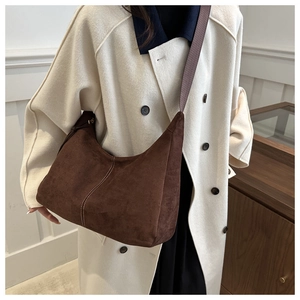 Detail of dark brown suede hobo bag with contrast stitching and wide shoulder strap
