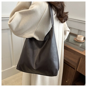Close-up of a large coffee brown leather tote bag with a textured matte finish