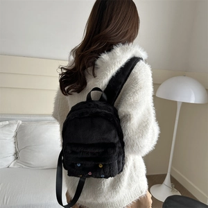Sac à dos mignon en fausse fourrure noire avec boutons colorés porté par un mannequin