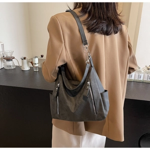 Detail of dark grey suede tote bag with double silver zippers and side pocket on shoulder