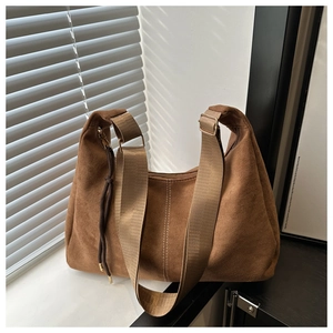 Detail of a brown suede hobo bag with white stitching and adjustable nylon strap