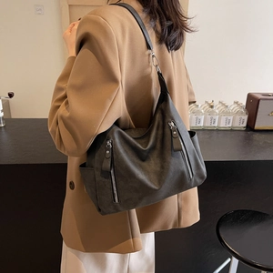 Large black matte leather hobo tote bag with silver zippers shown on shoulder