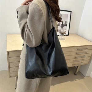 Minimalist large black PU leather tote bag shown on model in a modern home interior