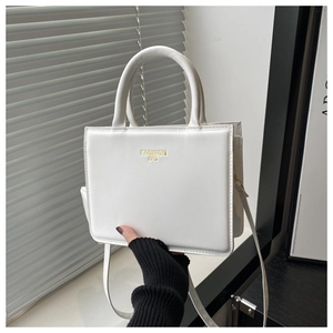 Gros plan détaillé d'un sac à main carré en cuir blanc avec un logo doré imprimé