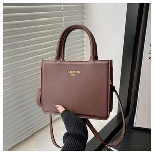 Détail du sac à main rectangulaire marron vintage avec lettrage doré et poignée chic