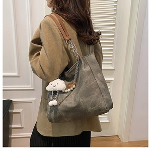 Detail of dark grey canvas tote bag with chain strap and cute cloud charm accessory
