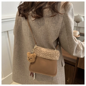 Détail d'un sac seau en cuir marron et polaire beige avec un adorable charm d'ours