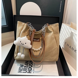 Close-up of khaki canvas tote with pearl chain and smiley cloud charm on display box