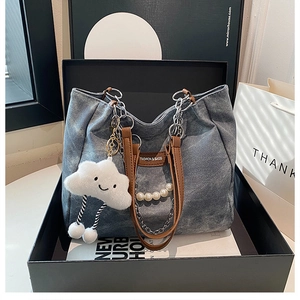Detail of denim tote bag featuring chunky silver chain, pearl beads, and cloud charm