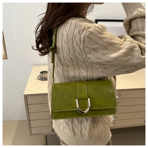 Detail of green retro shoulder bag with gold U-shaped buckle and knotted strap