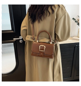Dettaglio di borsa vintage in pelle marrone con fibbia in metallo dorato e manico fisso