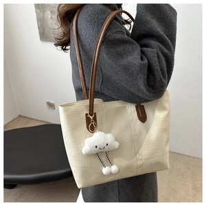 Detail of cream tote bag with pleated texture and cute white plush cloud charm