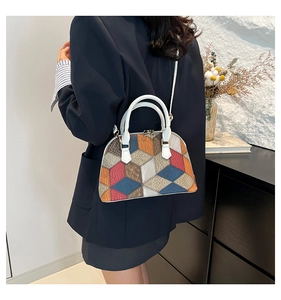 Macro view of shell-shaped handbag with geometric leather stitching and golden hardware