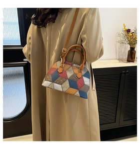 Detail of color-block shell bag with geometric leather patterns and brown top handle