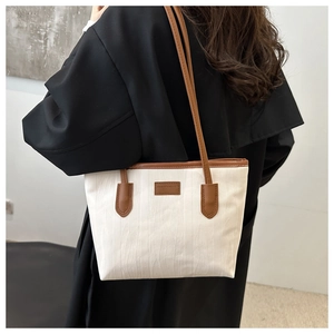 Detail of a large white tote bag with wave texture and brown leather accents on a model