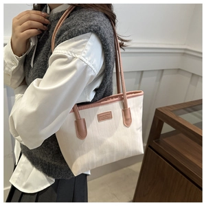 Close-up of white tote bag with pink trim, wavy texture, and elegant shoulder strap