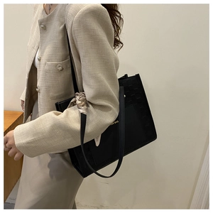 Detail of black woven tote bag with silk scarf handle and gold fashion bag logo