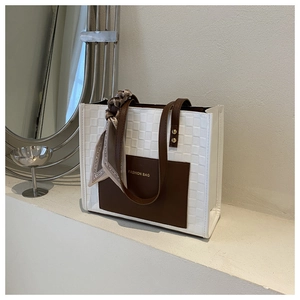 Detail showing checkered pattern tote bag with decorative silk scarf on brown handles