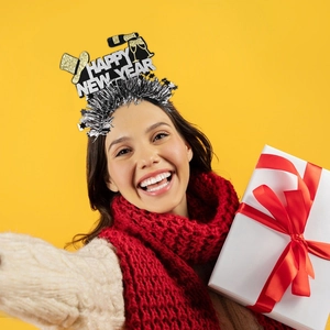 Detail of Happy New Year headband with champagne motifs on a smiling model with gift