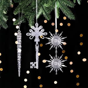 Close-up of clear acrylic icicle, key, and snowflake ornaments hanging on a Christmas tree