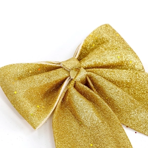 Glitzernde goldene Weihnachtsschleife als Christbaumschmuck und festliche Dekoration