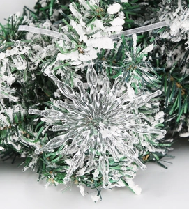 Macro detail of transparent star snowflake ornament on pine branch with fake snow background