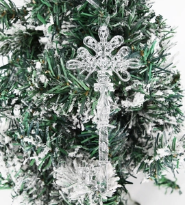 Detailed view of clear acrylic snowflake key pendant hanging on a snowy Christmas tree