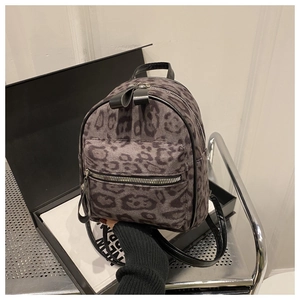 Vue détaillée d'un mini sac à dos imprimé léopard avec texture velours tenu par la main