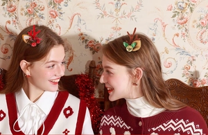 Détail de barrettes de Noël bois de renne avec baies rouges et petites cloches dorées