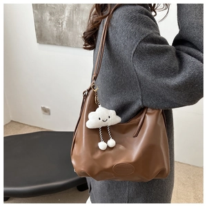 Detail of deep brown faux leather hobo tote bag featuring a cute plush cloud charm