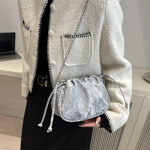 Silver pleated cloud bag with metallic texture and chain strap worn over the shoulder